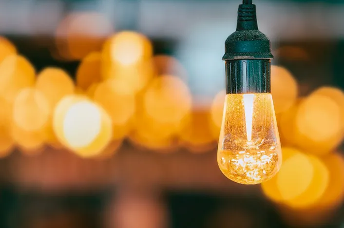 Ampolleta encendida con luces cálidas de fondo